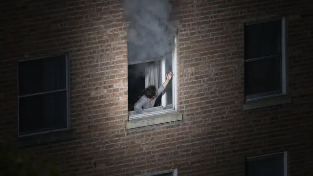 Concept illustration: seen from a drone, a person leans out of an open rear window and waves while smoke rolls out above them.